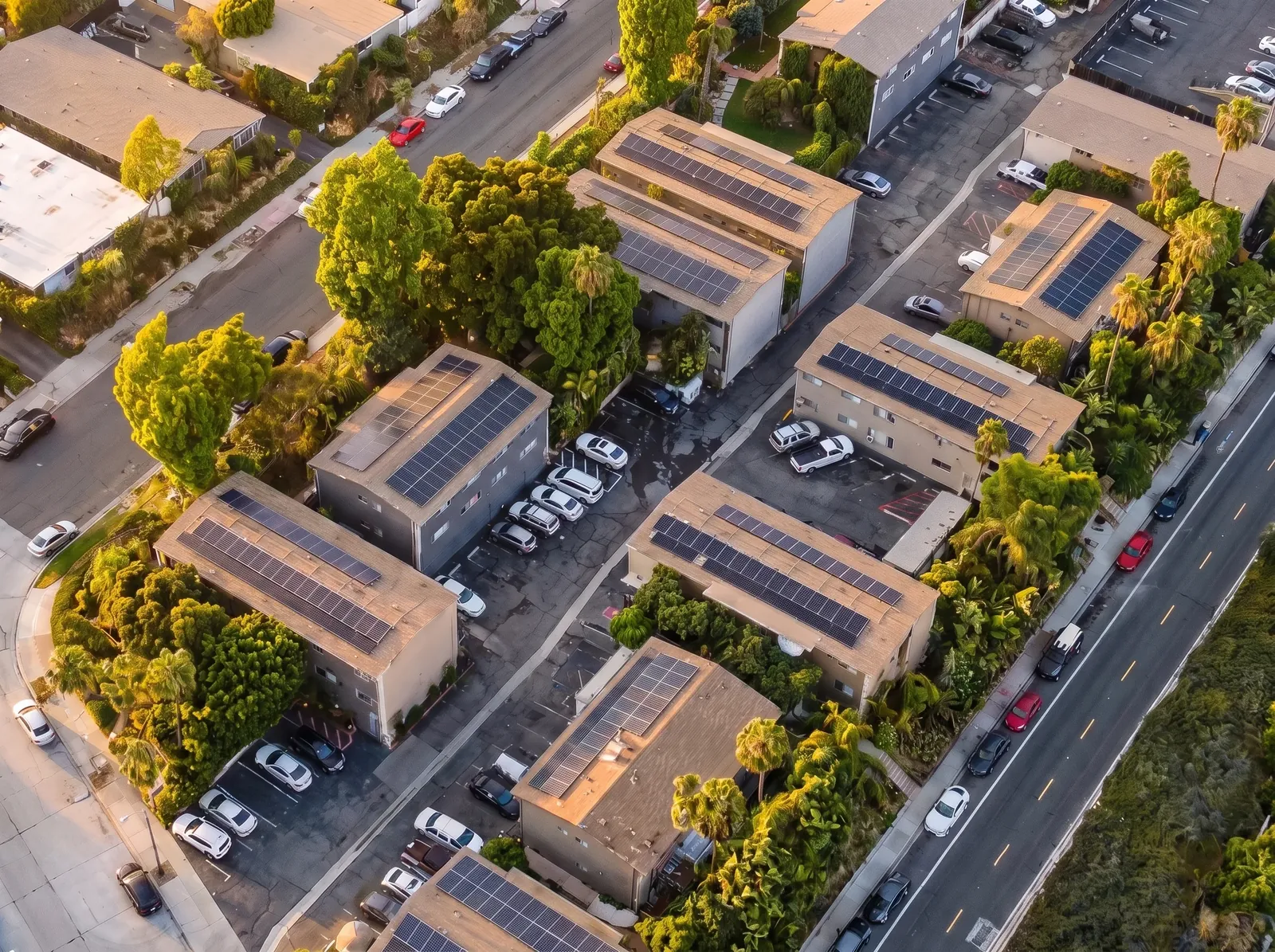 Aerial view of a multi-family apartment complex with rooftop solar panels and palm trees
